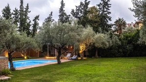 Un patio trasero con piscina, muro de ladrillo y césped.