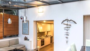 Una sala de estar moderna con un sofá, una mesa de centro y una cocina visible a través de una puerta abierta.