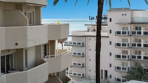 A multi-story building with balconies overlooking a beach.