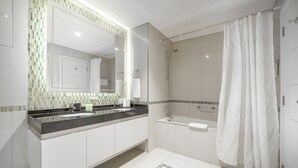 Un bagno moderno con un ampio specchio, una vasca da bagno e uno spazio doccia.