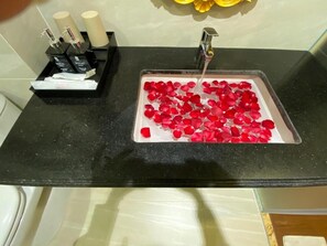 A bathroom sink with red rose petals and toiletries. - Hoang Gia I Hotel Yen Xa - by Bay Luxury (Hanoi)