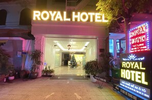 La façade de l’hôtel Royal, avec son grand panneau lumineux, un sapin de Noël et des plantes en pot.