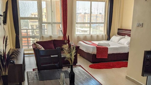 A hotel room with a dining area, a bed, and a view of the city. - City View Suites (Nairobi)