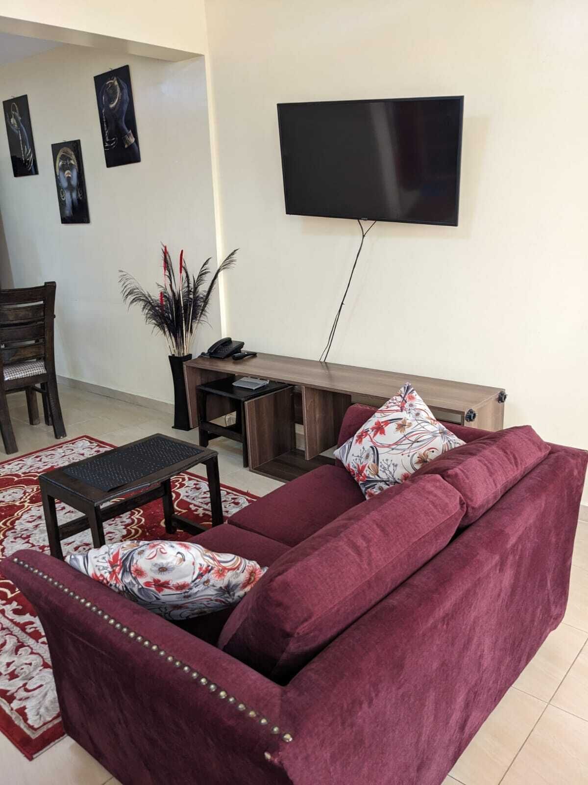 Una sala de estar con un sofá, una mesa de centro, un televisor montado en la pared y un banco de madera.