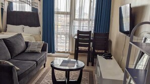 A living room with a sofa, a coffee table, a TV, and a desk. - City View Suites (Nairobi)
