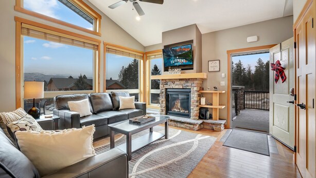 A spacious living room with a fireplace, large windows, and a cozy seating area.