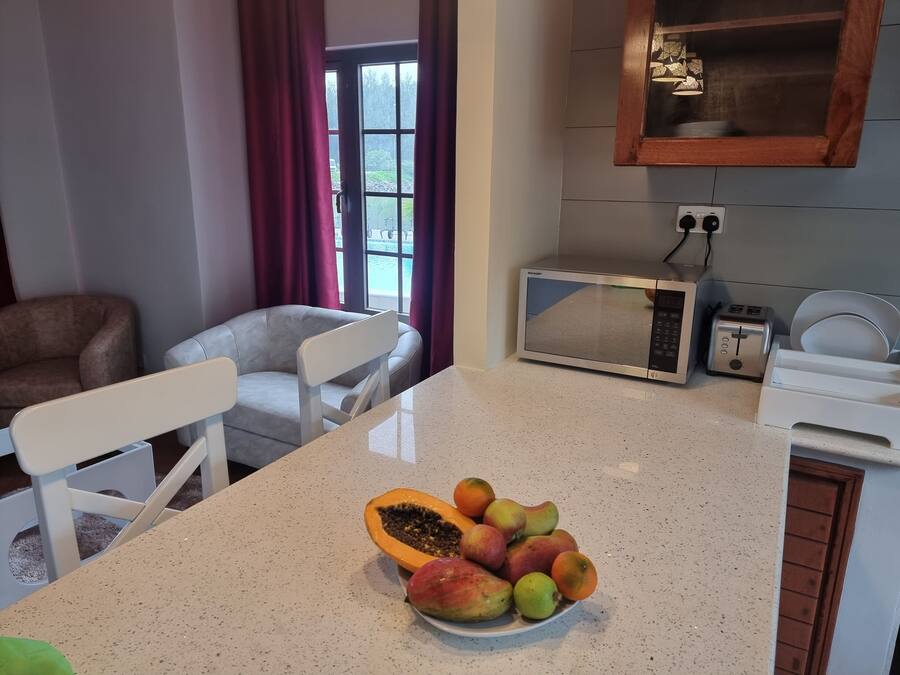 Una cocina con microondas, tostadora y un bol de fruta sobre la encimera.