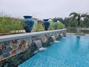 A swimming pool with stone walls and a waterfall feature. - Phoenix Luxury Self Catering Apartments (Mahé Island)