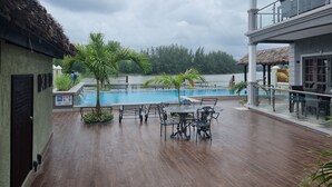 Zona de piscina con terraza de madera, asientos al aire libre y vista a un cuerpo de agua.