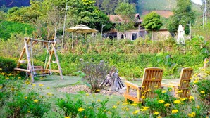 A garden with a swing set, wooden chairs, and a table. - Van Ho Ecolodge (Van Ho)
