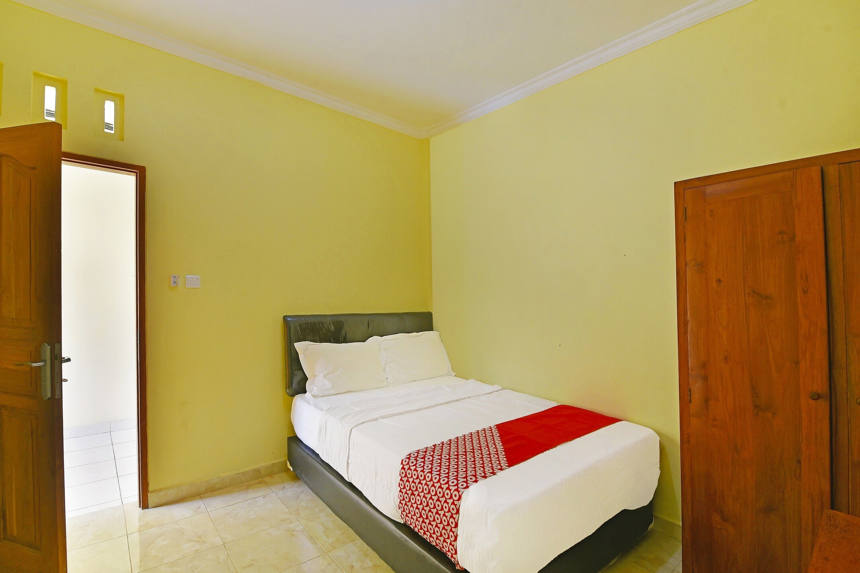 Quarto com cama, porta de madeira e parede amarela.