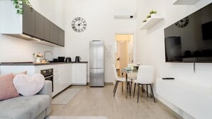 A modern kitchen with white cabinets, a stainless steel refrigerator, and a dining area with a white table and chairs. - New and cozy Apartment in Center (Milano)