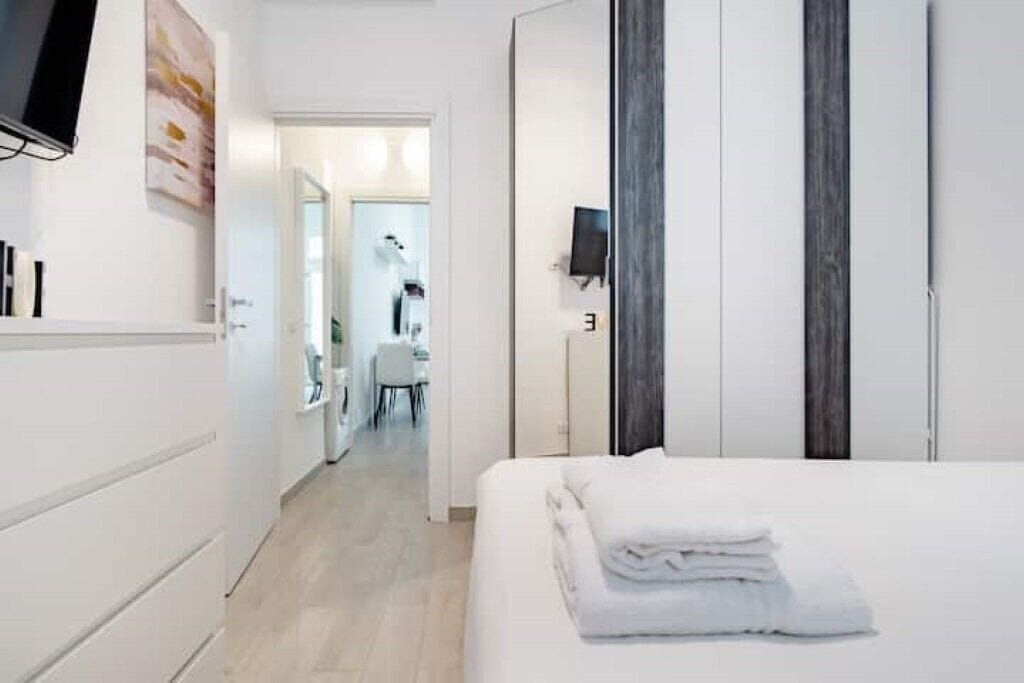Une chambre d’hôtel comprenant un lit, une télévision, une salle de bain avec un miroir et une porte donnant sur une autre pièce.