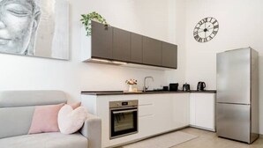 A modern kitchen with white cabinets, a built-in oven, a stainless steel refrigerator, and a clock on the wall. - New and cozy Apartment in Center (Milano)
