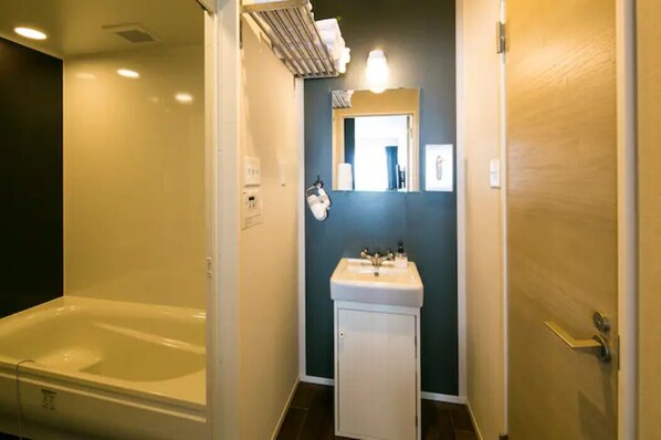 A bathroom with a bathtub, a sink, and a mirror. - ROI SPACE KAGOSHIMA (Kagoshima)