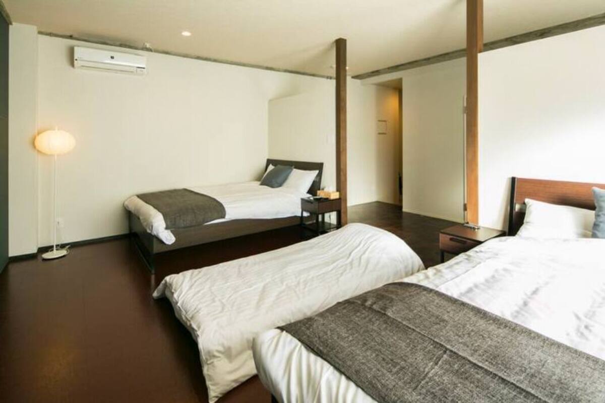 A hotel room with two beds, a bedside table, a lamp, and a large mirror.