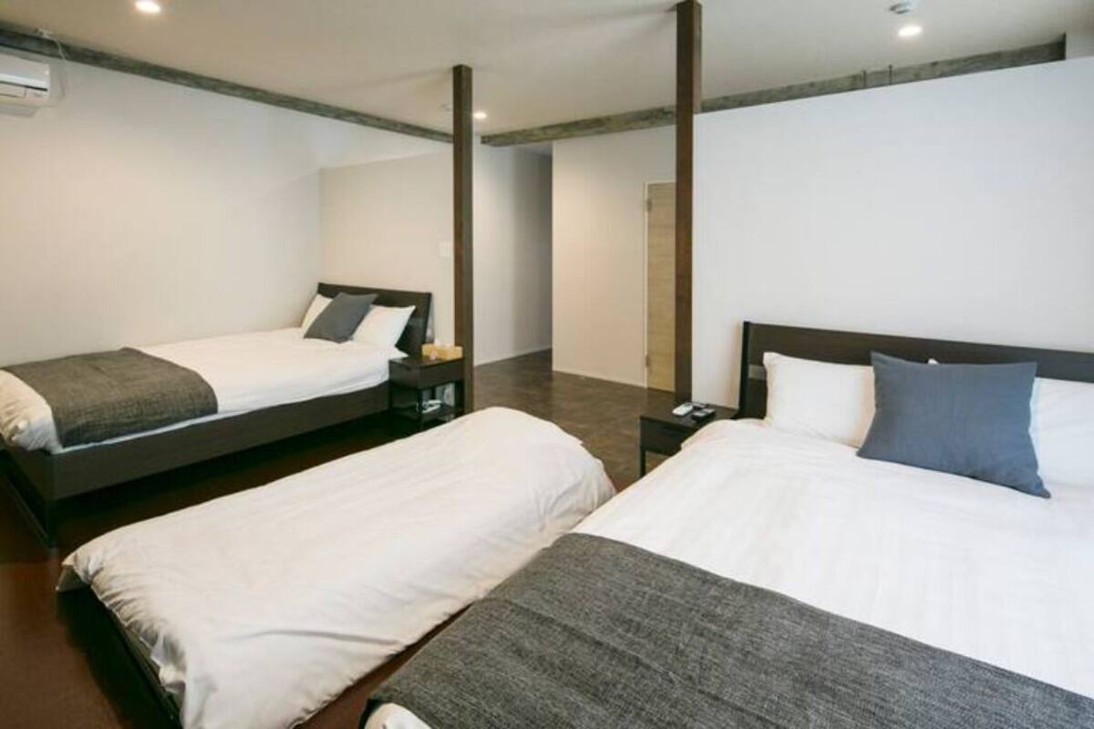A hotel room with two beds, a wooden ceiling, and a modern design.