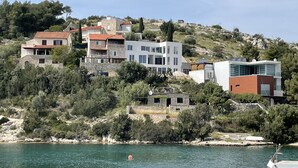 A coastal residential area with modern houses, a clear view of the sea, and a rocky hillside. - Villa More A-11 (Sutivan)