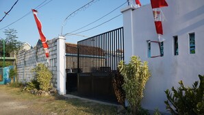 A gated property with a white exterior, a black metal gate, and a small garden area with rocks and plants. - OYO Life 93017 Kost H Soeroso (Situbondo)