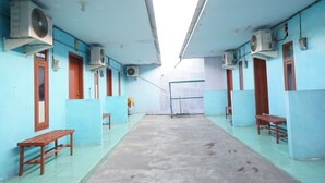 A corridor with blue walls, wooden benches, and air conditioning units. - OYO Life 93017 Kost H Soeroso (Situbondo)