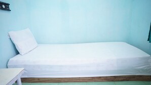 A single bed with a white mattress and pillow in a room with light blue walls and green tiled flooring. - OYO Life 93017 Kost H Soeroso (Situbondo)