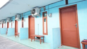 A row of rooms with blue walls and brown doors, each with a window and a bench outside. - OYO Life 93017 Kost H Soeroso (Situbondo)