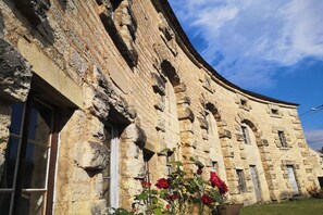 Un bâtiment historique en pierre, doté de fenêtres en arc de cercle et d’une façade incurvée.
