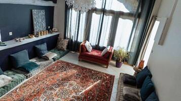 A living room with a large patterned rug, a red sofa, and a blue couch.