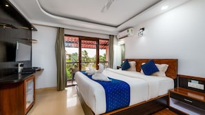Una habitación de hotel con cama, escritorio, televisor y aire acondicionado.