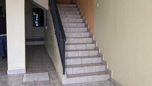 A staircase with beige walls and grey tiles leading to an upper floor. - Eilarose Suites (Ruiru)