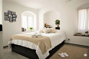 Ein modernes Schlafzimmer mit einem großen Bett, einer Zimmerpflanze und einem Fenster mit Vorhängen.