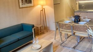 Un espace de vie moderne comprenant un canapé, une table à manger avec des chaises, une lampe et un escalier.