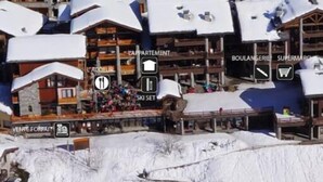 Une station de ski enneigée, avec des chalets en bois et un télésiège.