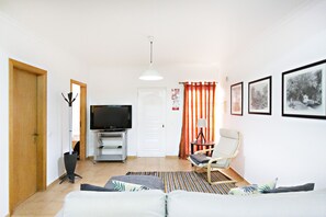 Una sala de estar con un sofá, un televisor, una silla y una puerta.