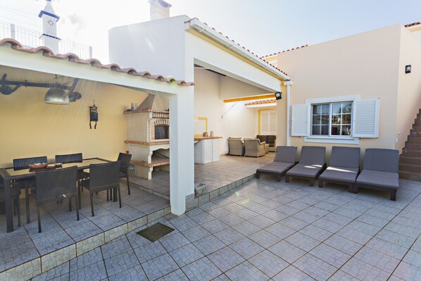 An outdoor patio with a dining area, lounge chairs, and a tiled floor.