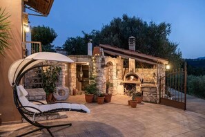 Un edificio de piedra con chimenea, asientos al aire libre y plantas en macetas.