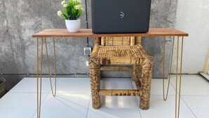Un ordinateur portable est posé sur une table en bois, avec une plante en pot à côté.