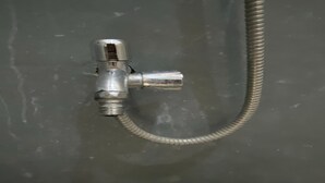 Un robinet de douche en métal avec un tuyau flexible.