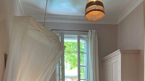 Un dormitorio con dos camas, un escritorio, una silla, un armario y una ventana con vistas a zonas verdes.