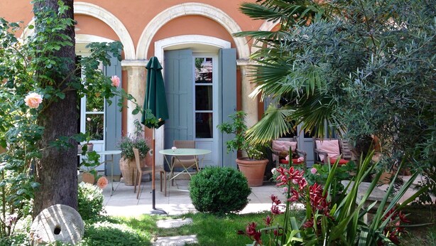 Un jardín con una mesa y sillas, un comedero para pájaros y una planta en maceta.
