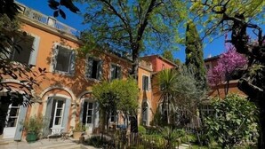 Zona junto a la piscina con vista despejada a un edificio con ventanas de arco y un balcón.