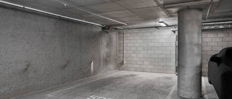 A parking garage with concrete walls, a pillar, and a car covered with a tarp.