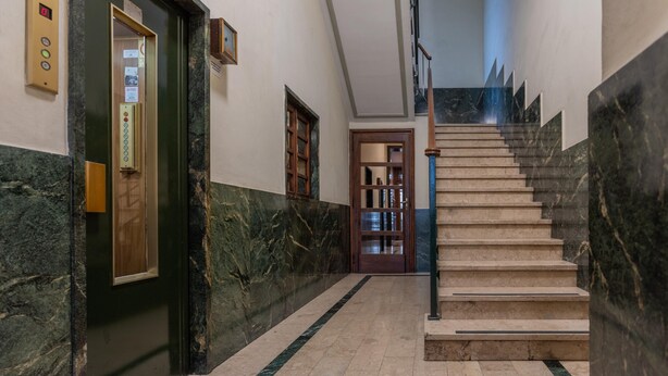 A marble-floored hallway with a staircase, an elevator, and a wooden door. - Amendola House by Wonderful Italy (Turin)
