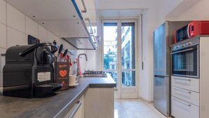 A modern kitchen with a built-in espresso machine, a sink, and a refrigerator. - Amendola House by Wonderful Italy (Turin)
