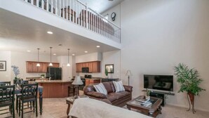 A spacious living area with a high ceiling, a dining area, and a kitchen. - Zions & St.George Adventure Base (Washington)