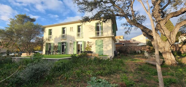 A two-story building with a garden in front, featuring a bench and outdoor seating. - Beautiful Villa, calm, 5 minutes walk to the beach. Walking distance to town. (Saint-Raphaël)