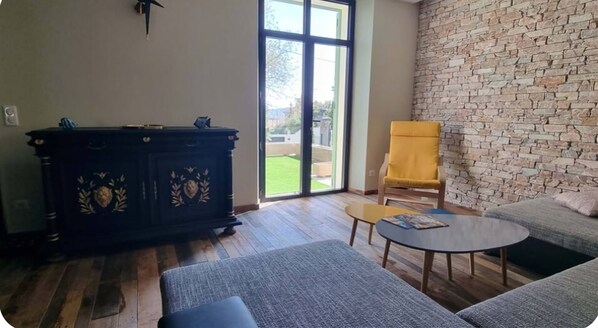 A living room with a stone wall, a sofa, a chair, a coffee table, and a cabinet.