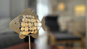 Koristeellinen kalapatsas, jossa on useita soikean muotoisia elementtejä ja joka on sijoitettu jalustalle.