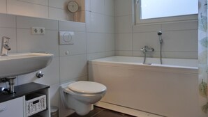 A bathroom with a toilet, sink, and bathtub. - Strandnahe Lage - MIT Balkon - Kaminofen- Wlan (Graal-Müritz)