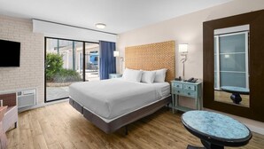 Quarto de hotel moderno com uma cama grande, uma escrivaninha, uma cadeira e vista para o exterior.